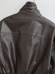 Detail view of the back stitching and faux leather texture of dark brown jacket