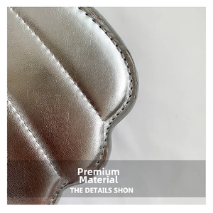 Macro shot of silver quilted faux leather with detailed lychee grain and precise stitching