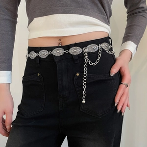 Detail view of vintage silver metal waist chain with engraved oval plates on black denim