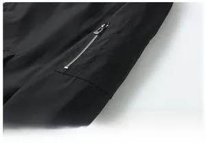 Detail of a tactical bomber jacket featuring a functional zipper pocket on the black sleeve