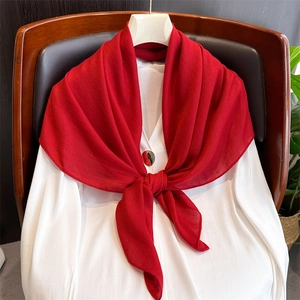 Sciarpa di lino rosso leggero drappeggiata con eleganza su una camicia bianca e sedia