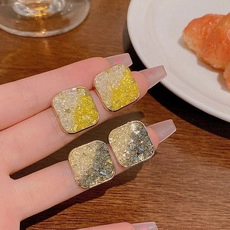 Dettaglio degli orecchini quadrati con zirconi micro-incastonati in giallo e grigio