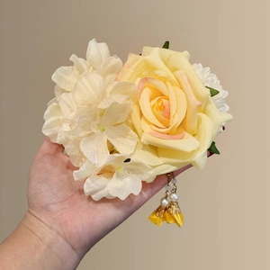 Detailed macro view of yellow silk rose hair clip with pearl tassels and hydrangea petals