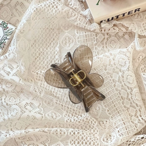 Détail d'une grande pince à cheveux papillon gris fumé sur fond de dentelle rétro
