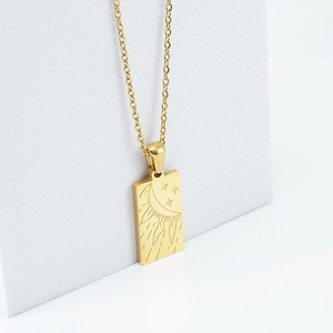 Nahaufnahme des goldenen Tarot-Anhängers mit Sonnen-, Mond- und Sternengravuren auf Metall