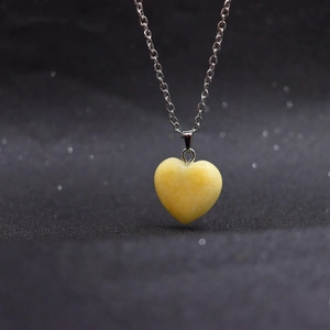 Macro shot of a yellow heart-shaped natural stone pendant on a silver link chain
