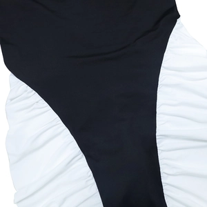 Détail d'une robe bicolore montrant le tissu noir et la texture froncée blanche