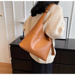 Gros plan du cuir grainé caramel d'un grand sac hobo avec une large bandoulière