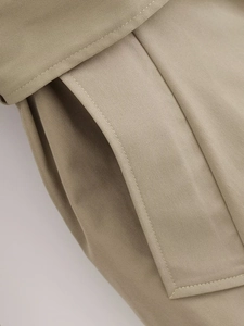Close-up detail of khaki twill trench coat fabric texture and premium stitching
