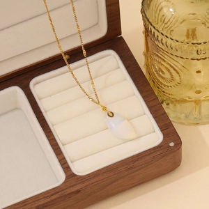 Detailaufnahme eines tropfenförmigen weißen Edelsteins an einer goldenen Kette