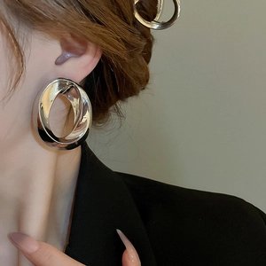 Close-up of a model wearing silver irregular hollow twisted oval earrings with metallic luster