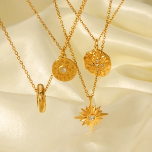 Detailed view of layered 18K gold plated stainless steel necklaces on white silk fabric