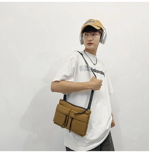 Detailed view of khaki nylon messenger bag with adjustable strap and front pockets on model