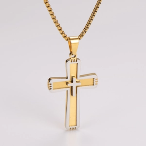 Close-up of a two-tone gold and silver layered cross pendant with a metal link chain