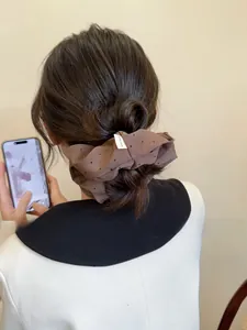 Close-up of brown polka dot hair scrunchie with handmade woven label in a ponytail