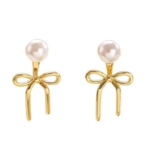 Gros plan sur les boucles d'oreilles nœud dorées avec perles blanches et texture chic