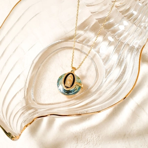 Macro shot of Virgin Mary pendant with blue-green crystal on gold stainless steel chain