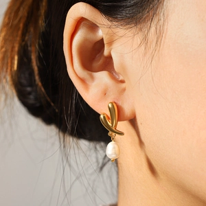Boucles d'oreilles élégantes en acier doré avec perles d'eau douce naturelles sur mannequin