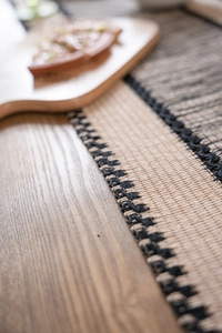 Macro shot of beige and black woven cotton table runner with textured boho patterns