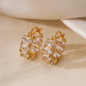 Exquisite 18K gold plated hoop earrings with oval zircon stones on beige fabric