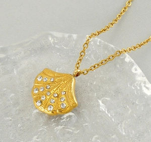 Detailed macro view of a gold shell pendant with micro-paved white rhinestones on the chain