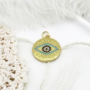 Detailed macro shot of a gold evil eye pendant with blue zircon on white lace and feather