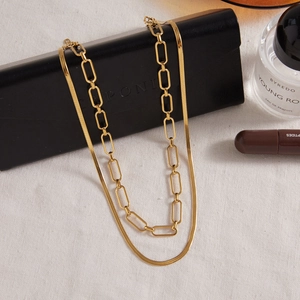 Detail of layered gold stainless steel snake chain and paperclip link necklaces on fabric