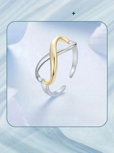 Macro shot of silver and gold infinity symbol open ring on a soft pastel background