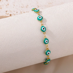 Detail of teal enamel Evil Eye charms on a gold-tone link bracelet for protection