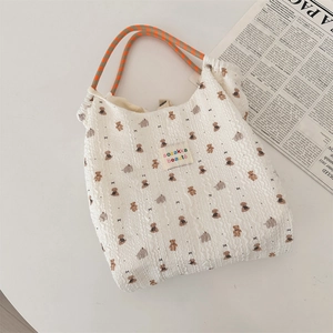 Dettaglio di una borsa tote bianca con stampa orso e manici intrecciati in stile zakka