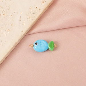 Close-up of handmade blue and green glass clownfish bead with gold side rings