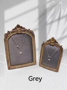 Detail of vintage gold picture frame displaying silver heart pearl and coin necklaces