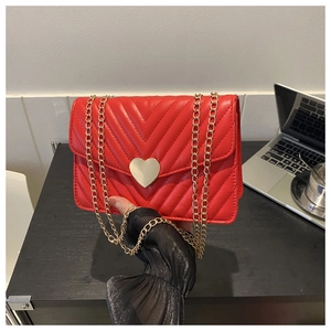 Dettaglio borsa a tracolla trapuntata rossa con chiusura a cuore d'oro e catena