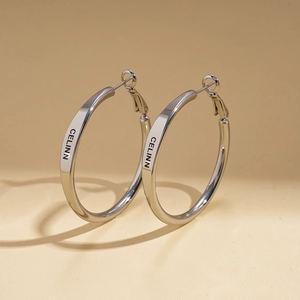 Close-up of polished silver hoop earrings with engraved minimalist CELINN lettering