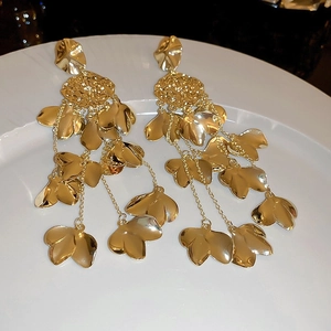 Macro detail of layered gold-plated leaf tassels and hammered texture on the earring