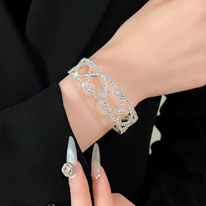 Detailopname van een zilveren crossover armband met zirkonia steentjes bij een model