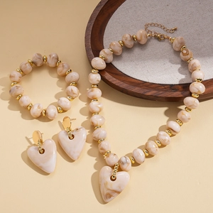 Detailed flat lay of acrylic marble beaded jewelry set with heart charms on wood