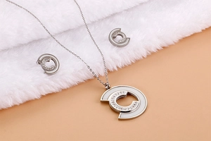 Detailed close-up of C-shaped stainless steel necklace and earrings set with shell inlay
