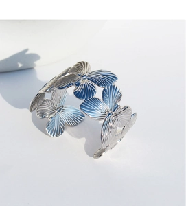 Macro shot of silver butterfly filigree detailing on the polished open metal cuff bracelet