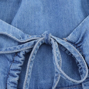Détail du tissu denim bleu montrant des côtés froncés élastiques et un cordon à nœud