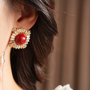 Close-up of vintage gold earrings with red round stone and crystal zircons on ear