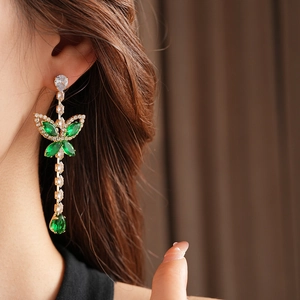 Detail of butterfly bow earrings with green water drop gems and small zircons on ear
