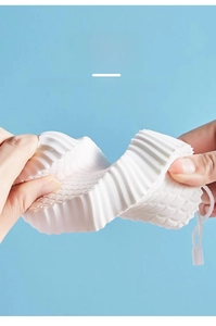 Close-up showing the soft elasticity and square texture of the white baby bath sponge