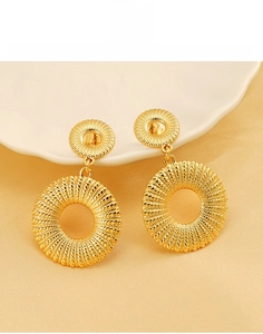 Macro view of gold titanium steel earrings featuring a woven hollow circular texture