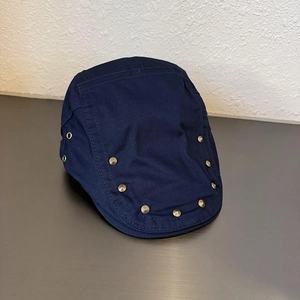 Dettaglio del berretto in tela blu scuro con eleganti decorazioni in rivetti metallici