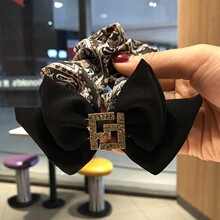 Detail of lace bow hair scrunchie featuring a silk pattern and a rhinestone metal buckle