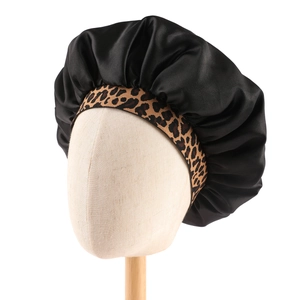 Detail of black satin sleep cap with leopard print elastic band on mannequin