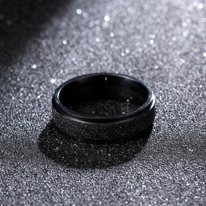 Close-up of a 6mm black matte titanium ring with a textured finish on a dark background