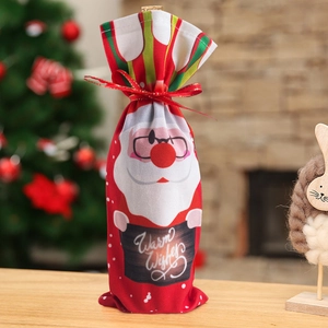 Détail d'un cache-bouteille Père Noël avec ruban rouge et texte de vœux chaleureux