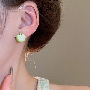 Close-up of a green apple zircon stud earring worn by a model in a natural setting